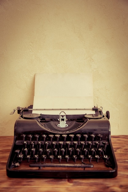 Máquina de escrever retrô com papel em branco na mesa de madeira. Vista do topo