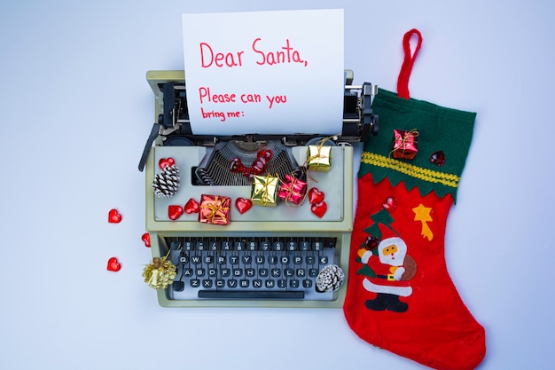 Máquina de escribir con la inscripción "Querido Santa", cajas de regalo y ramas de abeto en blanco