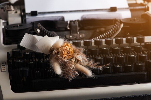 Máquina de escribir con letras rusas de cerca y flores secas