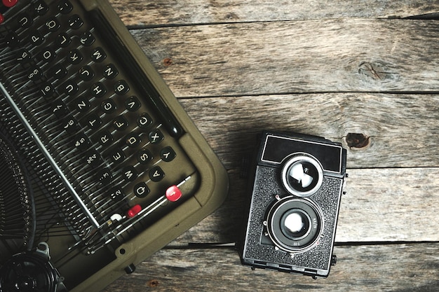 Máquina de escribir retro y cámara sobre un fondo de madera vieja con una vista desde arriba.