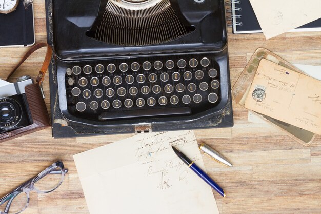 Máquina de escribir vintage negra con libros y correo antiguo en la mesa de madera