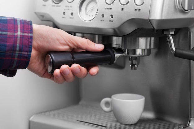 Máquina de espresso profesional que vierte café fresco de aspecto fuerte en una elegante taza de cerámica