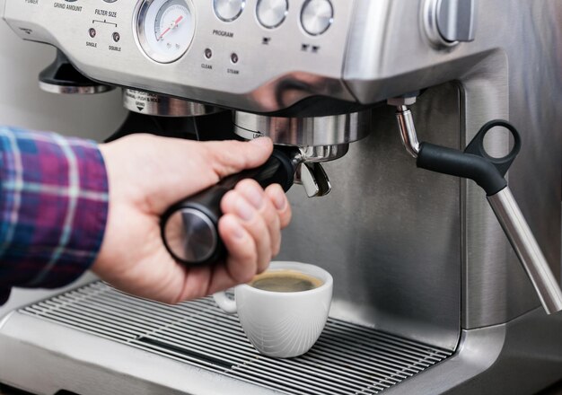 Máquina de espresso profesional que vierte café fresco de aspecto fuerte en una elegante taza de cerámica