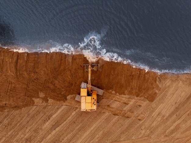 Máquina excavadora haciendo un movimiento de tierras en una fotografía aérea shore