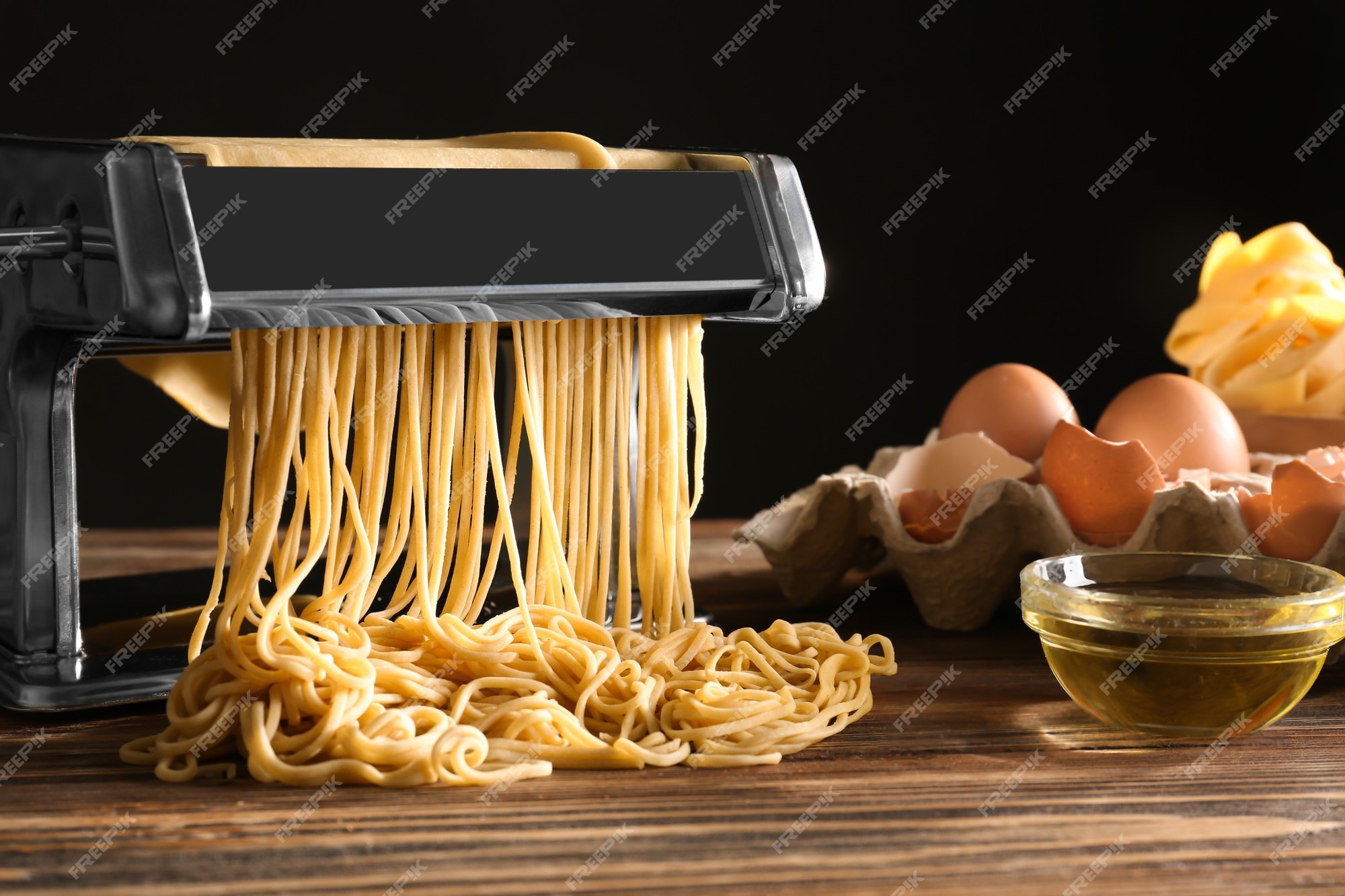 Máquina para hacer pasta de metal con masa y productos en la mesa de la  cocina