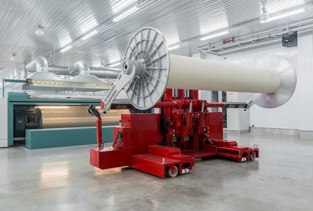 La máquina hidráulica de elevación levanta bobinas grandes. fábrica textil y de hilatura