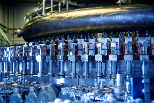 La máquina de llenado automática vierte agua en botellas de plástico para mascotas en una moderna planta de bebidas