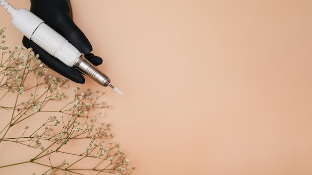 Una máquina para manicura de hardware profesional en la mano de una mujer sobre un fondo claro Equipo para el maestro del servicio de uñas Procedimientos cosméticos Copiar un espacio