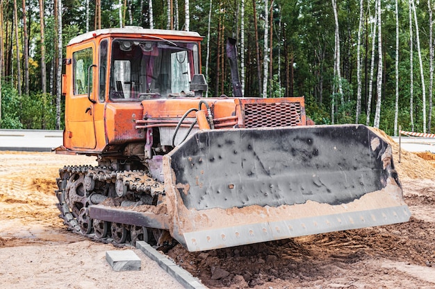 La máquina niveladora está nivelando el sitio de construcción. La excavadora con oruga está moviendo la tierra. De cerca. Maquinaria pesada de construcción.