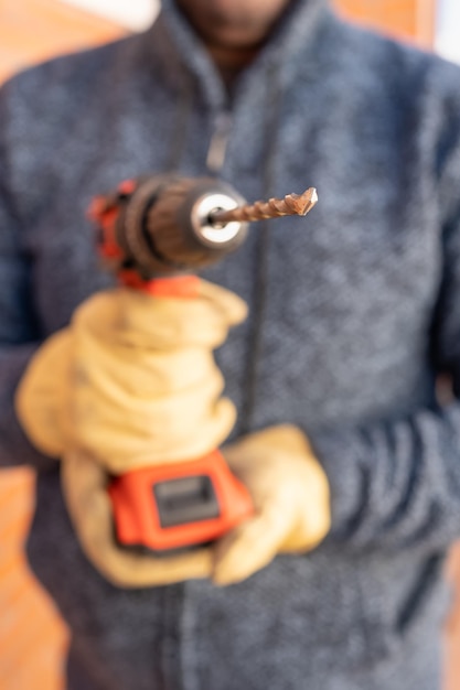 Foto máquina perforadora eléctrica sostenida por las manos de un hombre trabajador foto de fondo fuera de foco