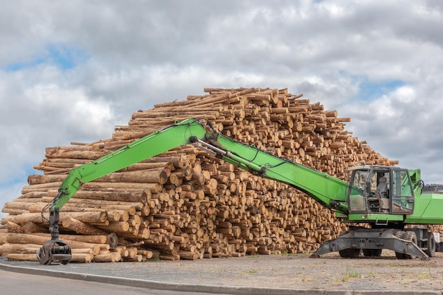 Foto máquina verde para transporte de toras e pilhas de árvores derrubadas para a indústria madeireira