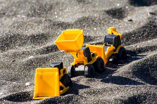 Maquinaria de construcción de juguete en arena negra Máquinas de juguete de colores amarillo y negro Excavadora excavadora