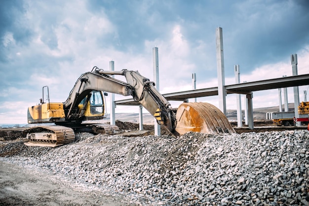 Foto maquinaria industrial en el sitio de construcción de carreteras excavadora pesada que mueve grava y rocas para la construcción de cimientos