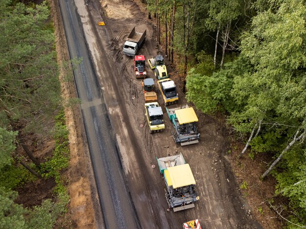 Máquinas de construção de estradas na estrada lateral. foto aérea de nova estrada incompleta no interior