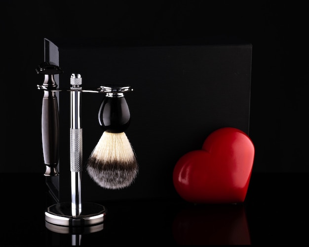 Maquinilla de afeitar y cepillo en soporte y caja negra, corazón rojo sobre negro