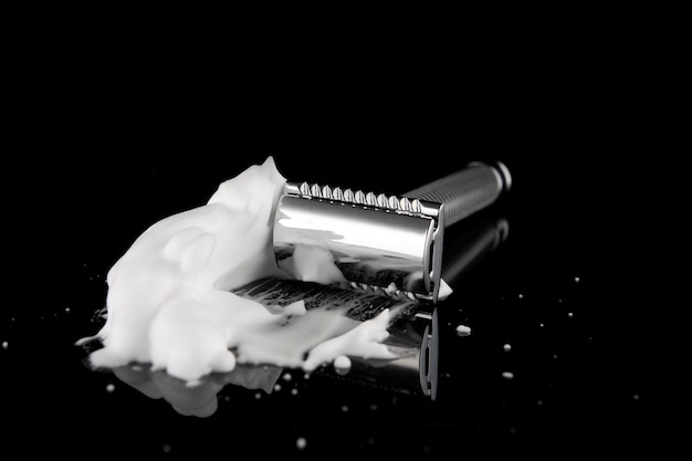 Maquinilla de afeitar vintage en espuma con reflejo en un fondo negro Espacio para texto