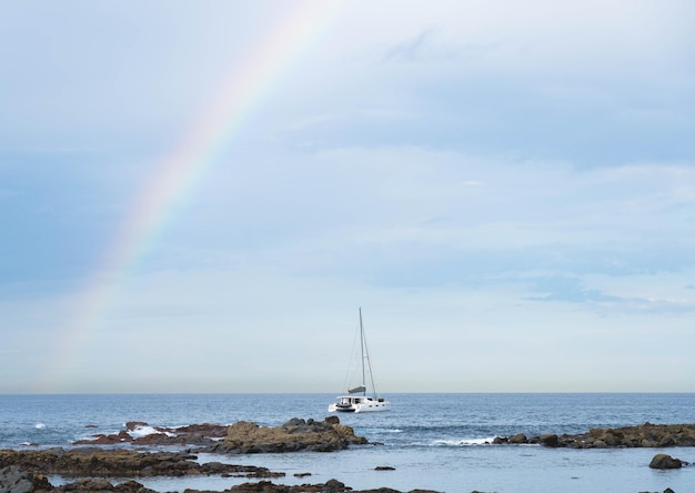 Mar azul y arco iris de velero en el cielo