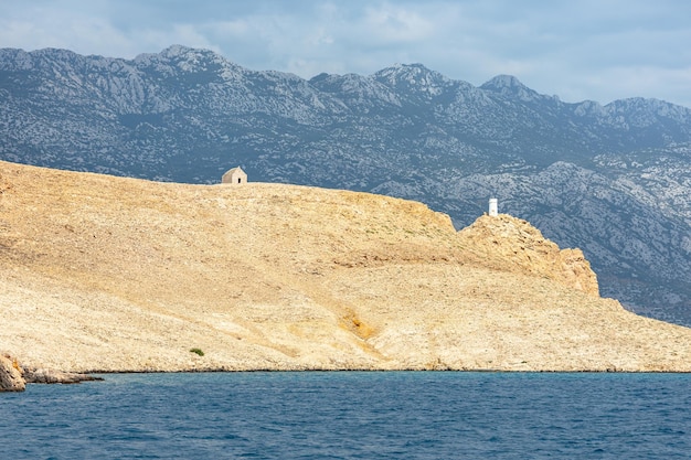 Mar azul e ilhas com um farol à beira de uma fotografia de paisagem montanhosa à beira-mar em um dia ensolarado