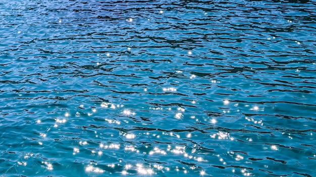 Mar azul en la luz del sol resplandor como concepto de vacaciones de verano de fondo de superficie
