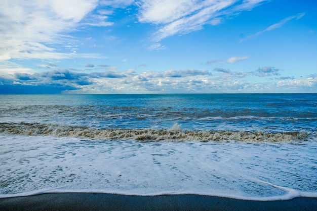 Mar azul y olas de cielo nublado