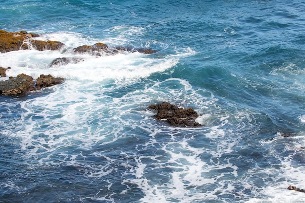 Mar azul y rocas rociar ola de asalto sobre rocas costa del mar rocoso