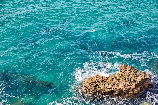 Mar azul rompiendo en las rocas de la costa