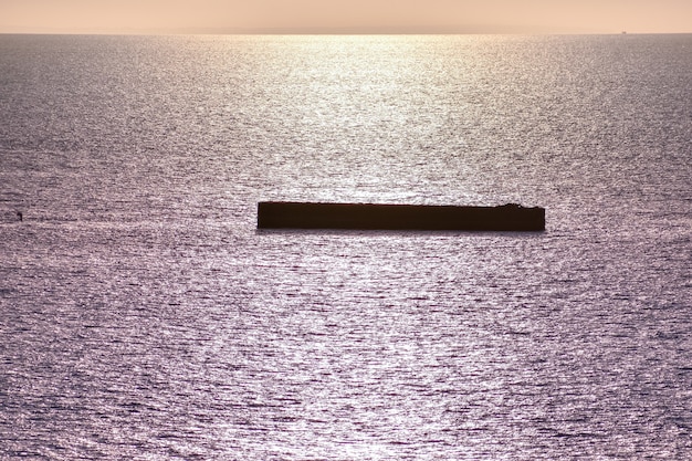 Mar en calma con cielo al atardecer. Horizonte colorido sobre el agua y la muralla atlántica. Normandía, Francia.