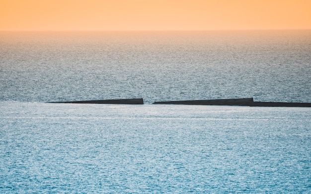 Mar en calma con cielo al atardecer. Horizonte colorido sobre el agua y la muralla atlántica.