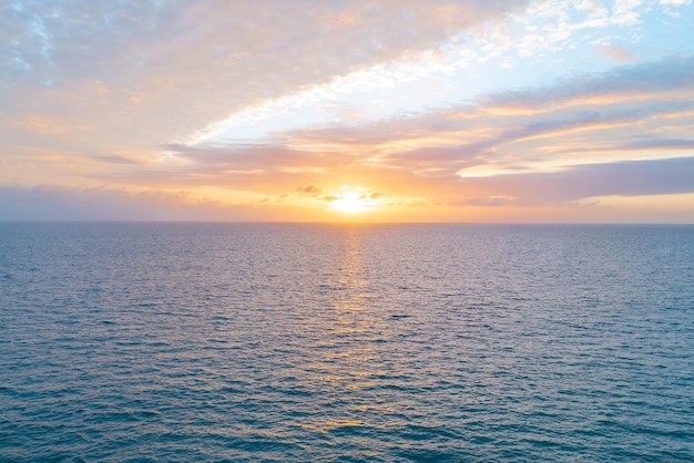 Mar en calma con cielo al atardecer y sol a través de las nubes sobre el océano y el paisaje marino de fondo del cielo