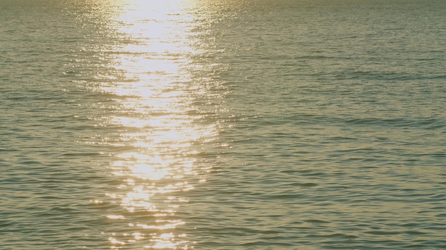 Mar calmo com brilho solar pontos de laranja lindo brilhando são vistos na superfície da água em câmera lenta