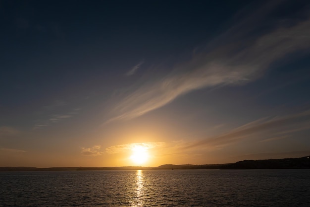 Mar calmo com céu pôr do sol e sol através das nuvens sobre o mar