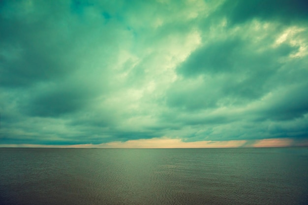 Mar calmo e tranquilo com o céu nublado ao pôr do sol