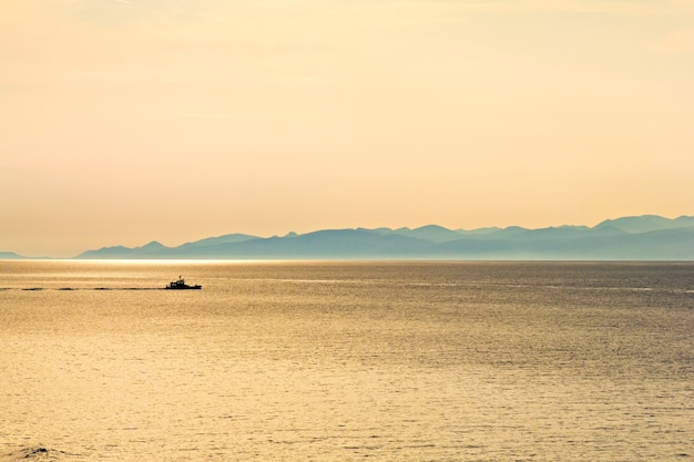 Mar, colinas e barco ao pôr do sol