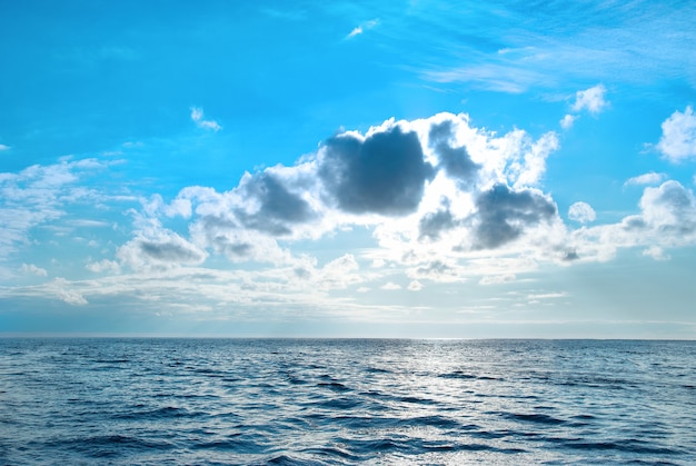 Mar com água azul, céu e nuvens. pôr do sol acima da paisagem marinha