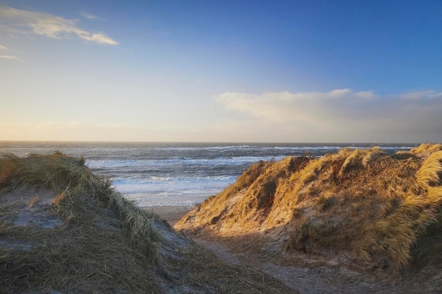 Foto mar do norte tempestuoso ao pôr-do-sol na cidade costeira dinamarquesa de hvide sande