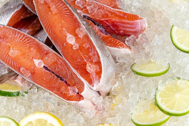 mar fresco oceano peixe vermelho cortado em pedaços, deitado no gelo, sem cabeça, cereja, limão fatiado e lima