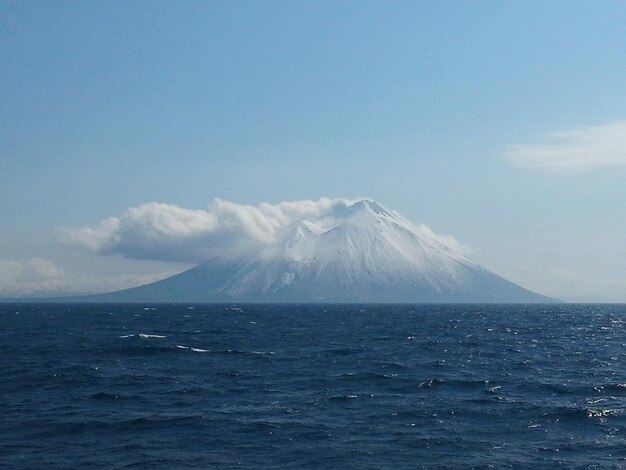 Foto mar por montaña cubierta de nieve contra el cielo en iturup