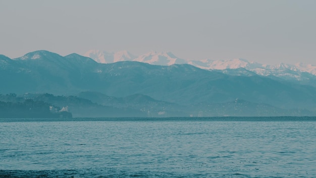 Mar por montañas cubiertas de nieve contra un cielo despejado en un día soleado cerca de la ciudad de Kobuleti Adjara Georgia