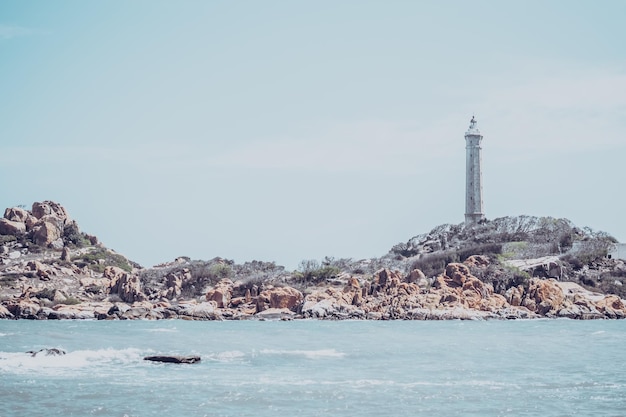 Mar naturaleza vista panorámica paisaje fondo Océano acantilados rocosos isla boscosa Cielo azul claro Faro en la cima de la montaña Señal advierte a los marineros naufragio concepto de viaje esperanza propósito de la vida