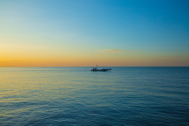 mar y pequeños barcos de pesca por la mañana, un pequeño barco de pesca en medio del mar al atardecer