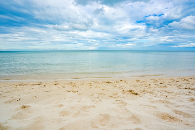 Mar de playa de arena con cielo azul y nubes