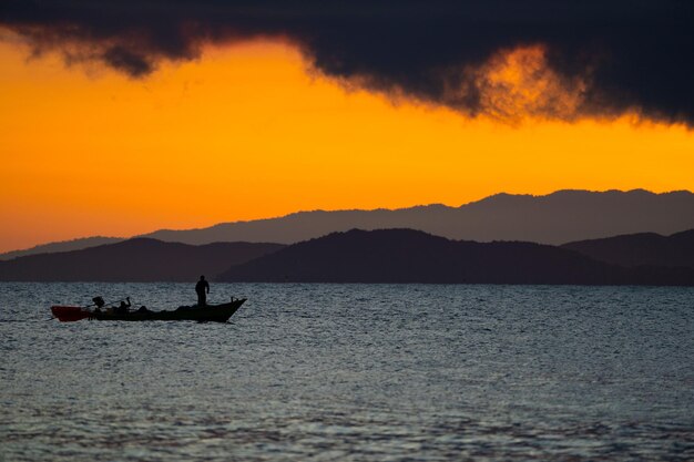 Mar de Tailandia en el crepúsculo con silueta barco y pescador en el mar