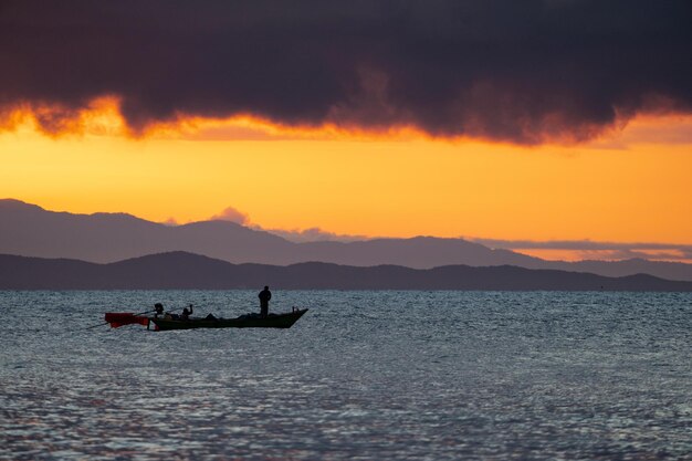 Mar de Tailandia en el crepúsculo con silueta barco y pescador en el mar