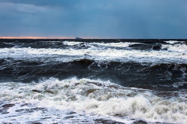 Un mar tormentoso con un barco en la distancia.