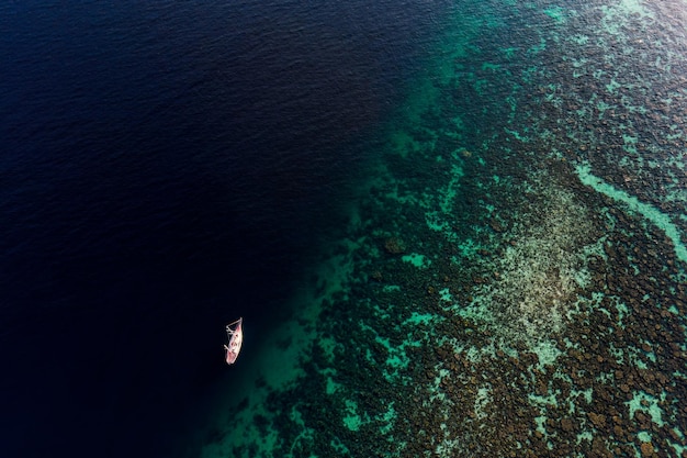 Mar tropical cênico com recife de coral e barco navegando no verão