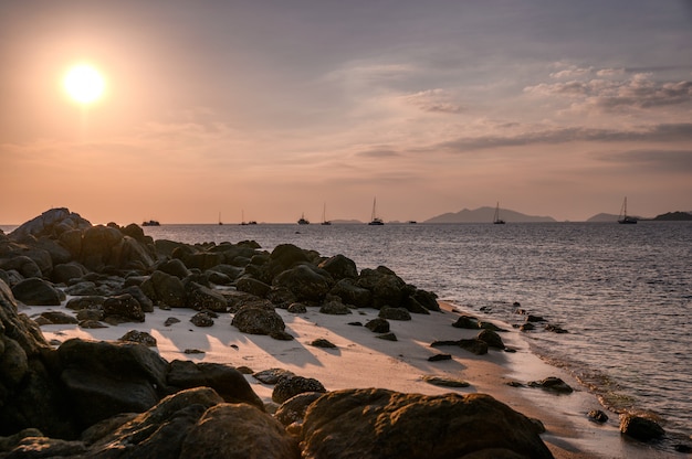 Mar tropical com pedras no litoral ao pôr do sol