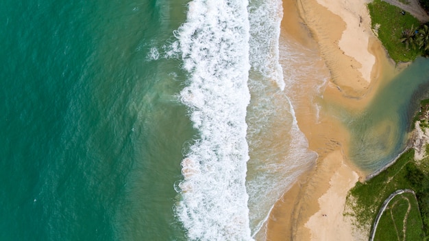 Mar tropical y onda que se estrella en la orilla arenosa en la playa de karon en la cámara del abejón de la vista aérea de phuket Tailandia de arriba hacia abajo.