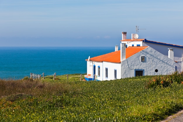 Mar turquesa, cielo azul y casa blanca en Portugal. Tiro horizontal