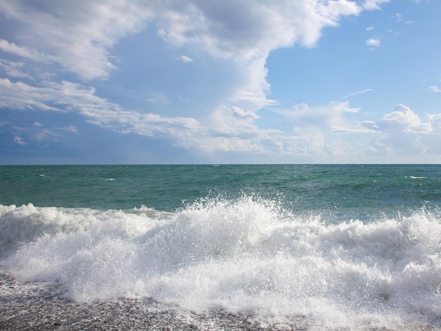 Mar turquesa da praia da paisagem pitoresca com ondas e espuma e nuvens bonitas no céu