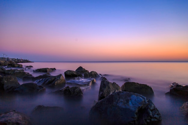 Mar vazio e rochas durante o pôr do sol com Silky Sea por causa da longa exposição via imagem de filtro ND para design